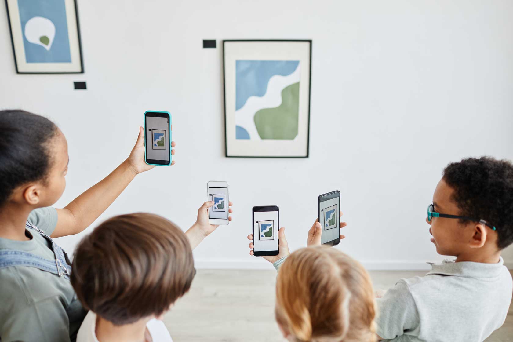 Digitale Bildung in der Ausstellung – mit Actionbound kreativ lernen Kinder mit Smartphones in einer Galerie, die mit einer App interaktiv ein Kunstwerk erkunden
