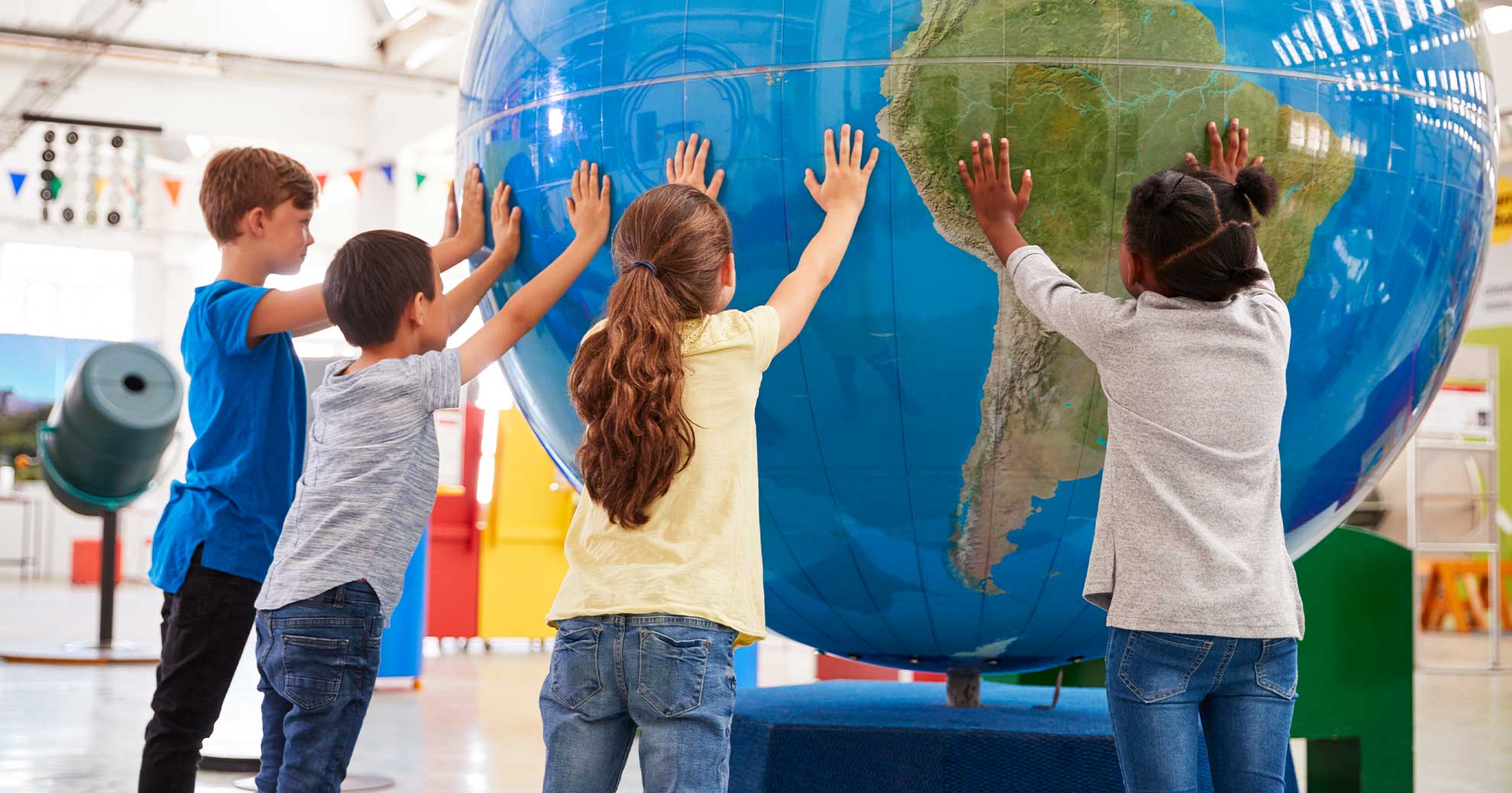 Schulkinder berühren einen überdimensionierten Globus in einem Ausstellungsraum