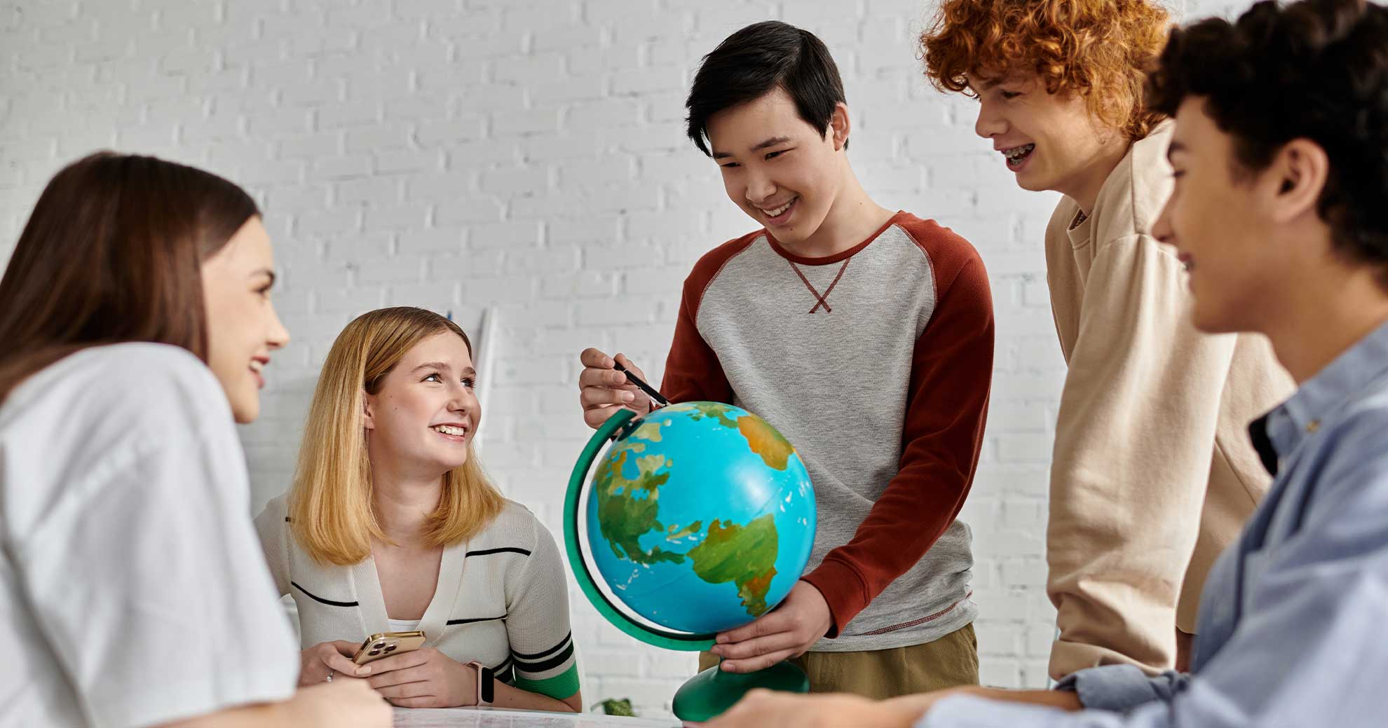 Jugendliche sitzen in einer Lerngruppe und diskutieren über einen Globus