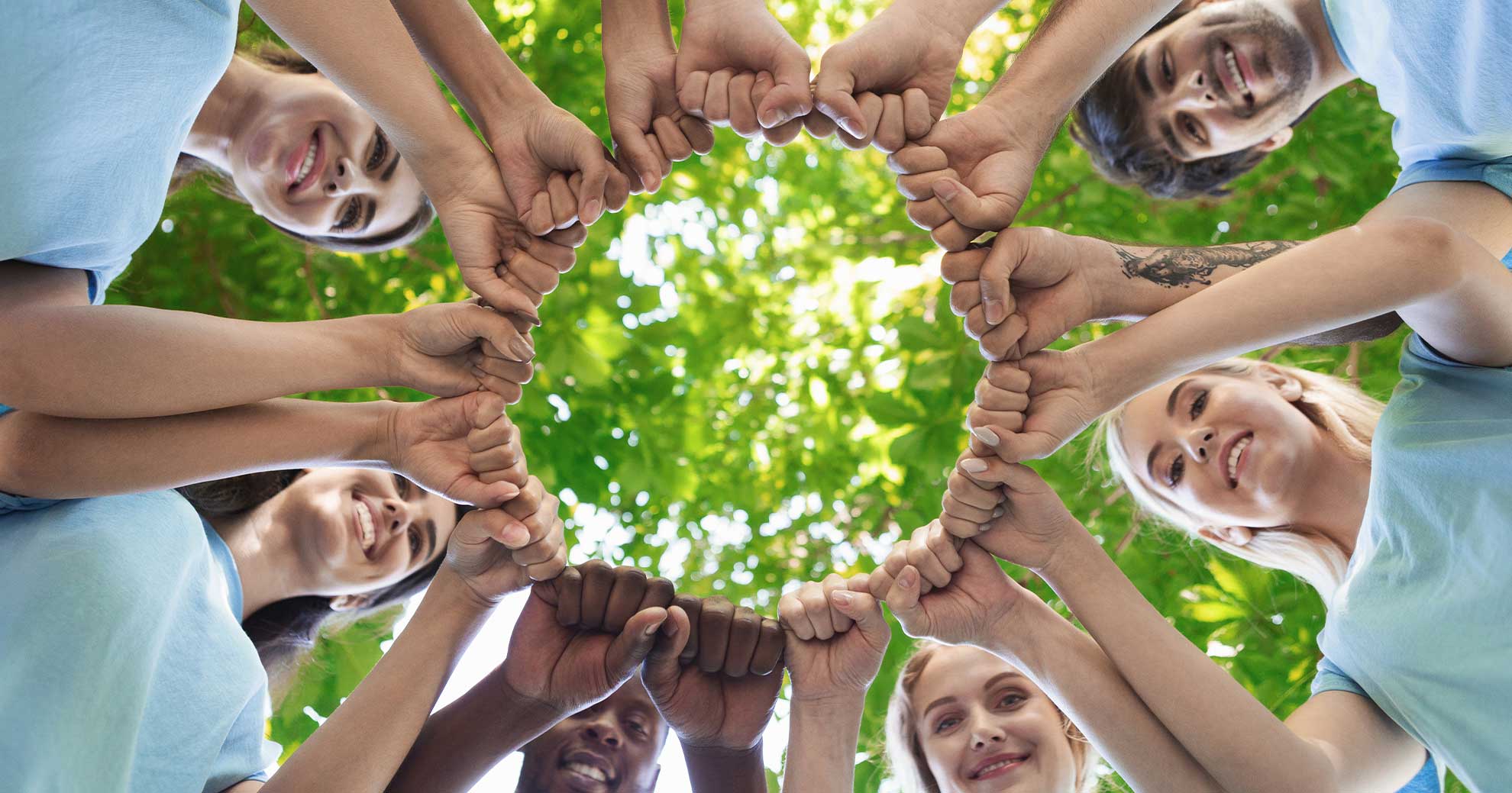 Jugendliche im Kreis – gemeinsam für den Klimaschutz : Jugendliche stehen im Kreis und berühren sich gegenseitig mit den Fäusten – Symbol für Zusammenhalt und Teamwork beim Klimaschutz