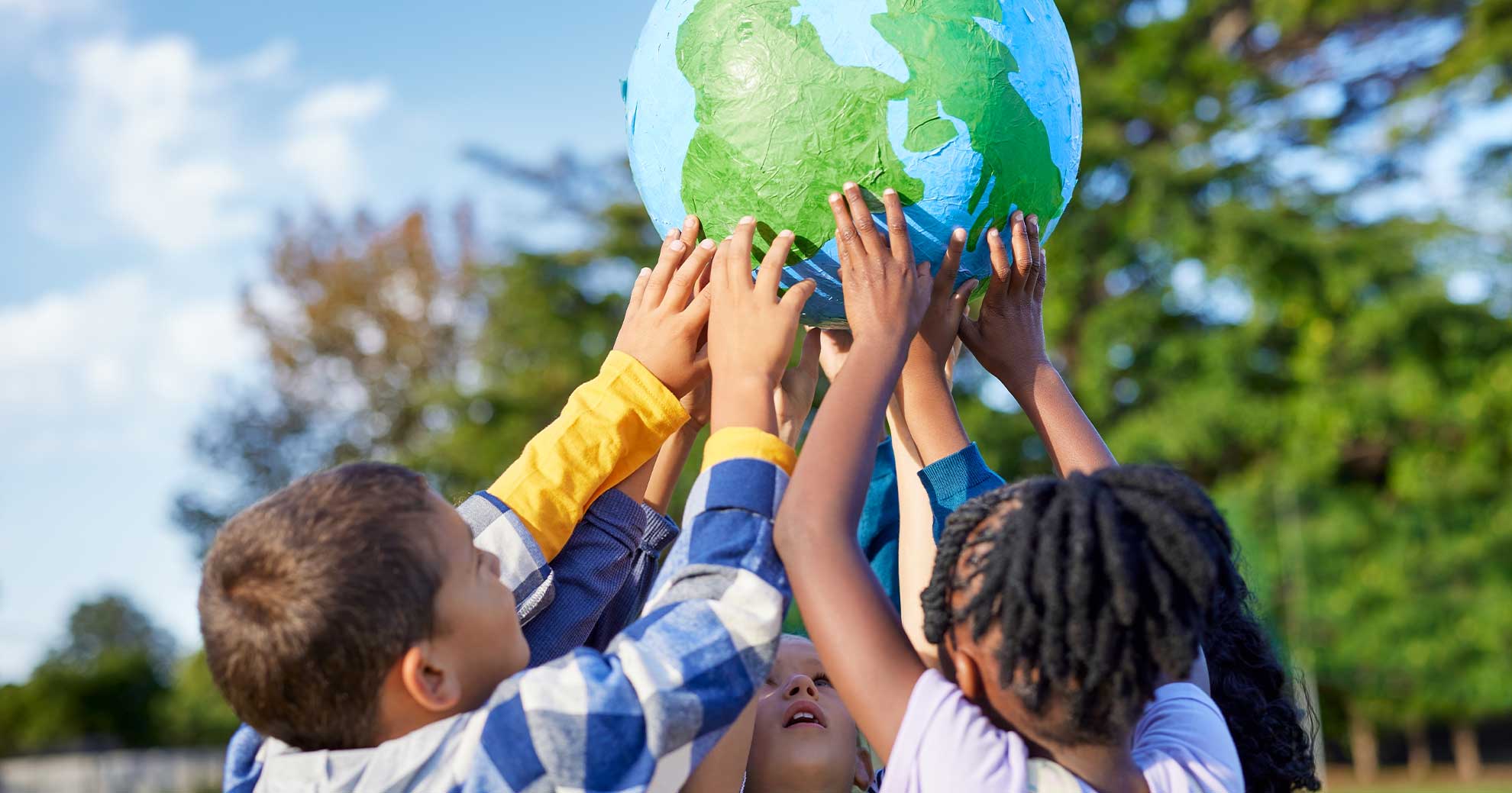 Kinder im Klassenzimmer heben gemeinsam eine Weltkugel hoch – symbolisch für globales Denken und Klimabewusstsein