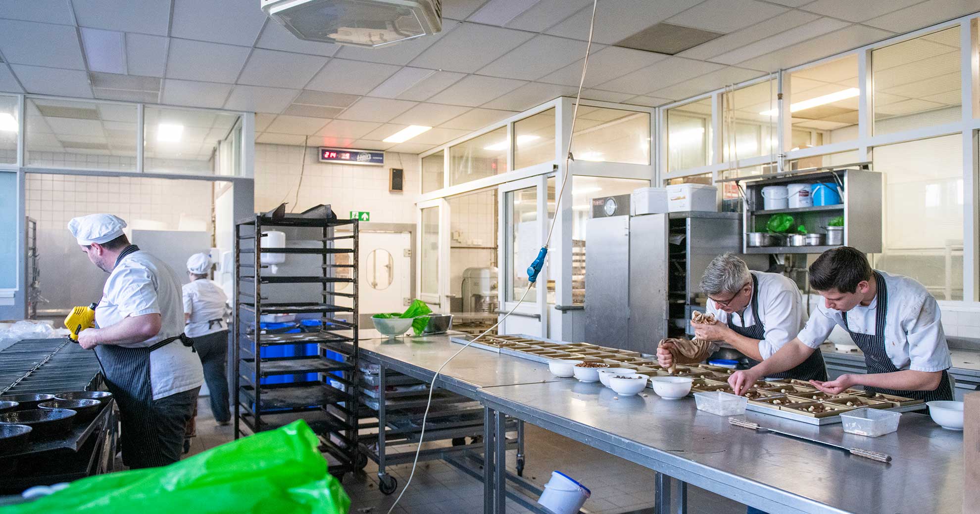 Culinary Kiosk – Nachhaltige Küchenpraxis gegen Lebensmittelverschwendung Köchinnen und Köche bereiten Mahlzeiten in einer Großküche vor, Fokus auf nachhaltige Speisenzubereitung und Abfallvermeidung, Culinary Kiosk Berlin